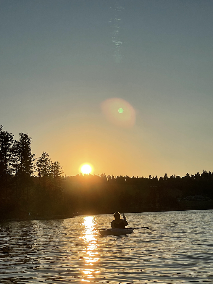 A photograph of Beth sitting in a kayak around sunset