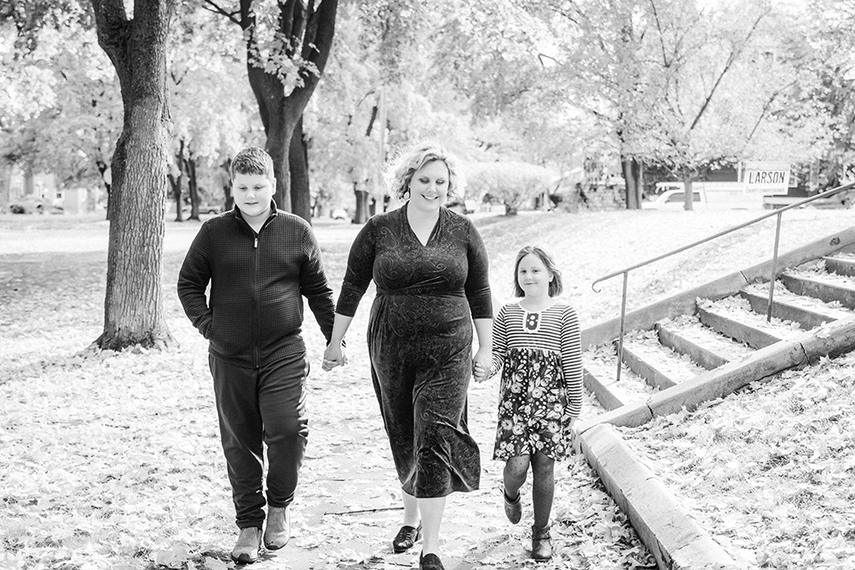 A vlack and white photograph of Beth walking with her children in Kalispell